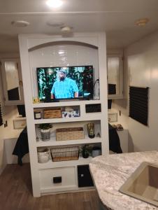 a living room with a tv in a white shelf at Camper Rental in Saint Helena Island