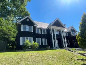 a black house with white windows on a lawn at Lodge Kent & Cottage Kent in Hokuto