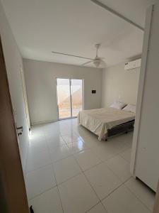 a white bedroom with a bed and a ceiling fan at Casa TS Morro Branco in Beberibe