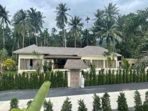 a white house with palm trees in the background at Ubuntu Villa in Ko Phangan