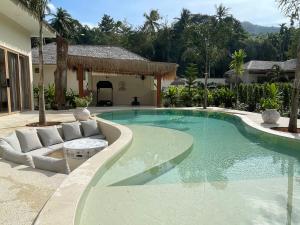 a swimming pool with a couch and a chair next to a house at Ubuntu Villa in Ko Phangan