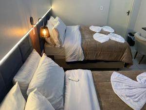 two beds in a hotel room with white pillows at Pousada HG-102-Suíte in Vila Nova do Sul