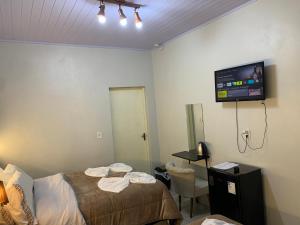 a bedroom with a bed and a tv on the wall at Pousada HG-102-Suíte in Vila Nova do Sul