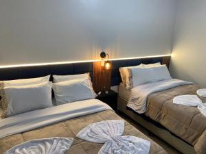a bedroom with two beds with white pillows at Pousada HG-102-Suíte in Vila Nova do Sul