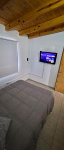a room with a bed and a tv on the wall at Depto El Mirador in Plaza Huincul +1 photo