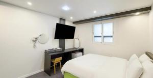 a bedroom with a bed and a desk with a television at Hotel Barley Field Seoknam in Incheon