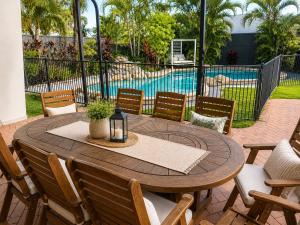 a round wooden table with chairs and a pool at Charming & Spacious 5 Bedroom Bayside House with Pool in Birkdale