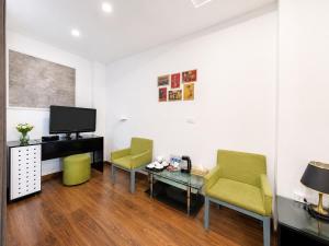 a living room with two chairs and a table and a tv at Valoria Legend Hanoi Hotel in Hanoi +39 photos
