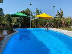 a swimming pool with two umbrellas and a swimming pool at Kep Orchid Cafe in Phumĭ Dâmnăk Châng'aeur