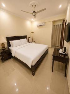 a bedroom with a large white bed and a table at The Corvane Residence in Islamabad