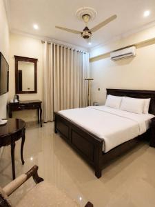 a bedroom with a bed and a table and a desk at The Corvane Residence in Islamabad
