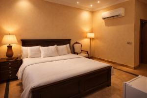a bedroom with a large bed with white sheets and a lamp at The Corvane Residence in Islamabad +19 photos