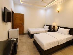 a hotel room with two beds and a television at The Corvane Residence in Islamabad