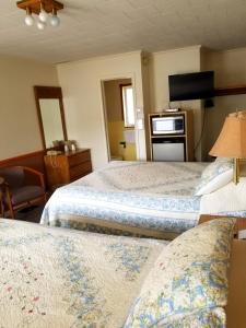 a hotel room with two beds and a television at Belaire Motel in Norton Shores
