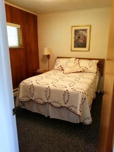 a bedroom with a bed with a white blanket at Belaire Motel in Norton Shores