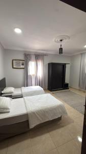 a bedroom with two beds and a flat screen tv at الدانه1 in Al Wajh