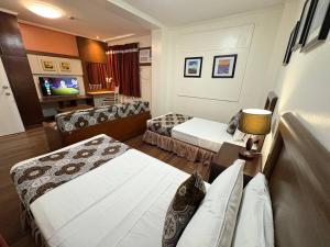 a hotel room with two beds and a television at 1775 Adriatico Suites in Manila