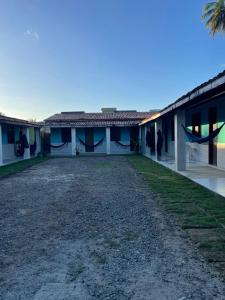 a house with a gravel driveway in front of it at Pousada Taquarí Guaibim in Valença