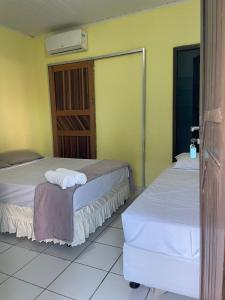 two beds in a room with yellow walls at Pousada Taquarí Guaibim in Valença