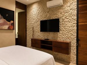 a bedroom with a television on a stone wall at Hotel Travertino in Mérida