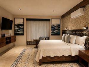 a hotel room with a bed and a flat screen tv at Hotel Travertino in Mérida +32 photos