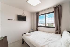 a bedroom with a white bed and a window at Nawin Hotel Donmueang in Thung Si Kan