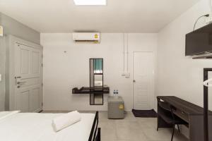 a white room with a bed and a desk at Nawin Hotel Donmueang in Thung Si Kan