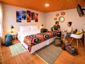 two people sitting in a bedroom with a large bed at La Casa del Molino Blanco B&B in Baños