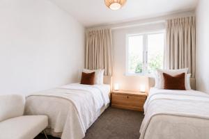 two beds in a room with a window at Tresco Apartments - Quiet Luxury in the Heart of Blenheim in Blenheim