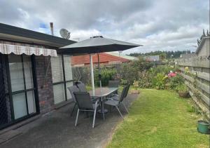a patio with a table and chairs and an umbrella at Peaceful BnB in Rotorua