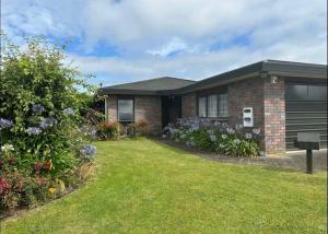 a brick house with a yard with flowers at Peaceful BnB in Rotorua