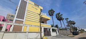 a yellow building with palm trees in front of it at Taj Palace in Covelong