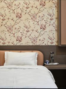 a bedroom with a bed with a floral wallpaper at Green Villa - Luxury Rooms at peaceful location -200 mtrs away from Bus Stand -500 mtrs from Udaipur Railway Station - Family Suites w Kitchen also available in Udaipur