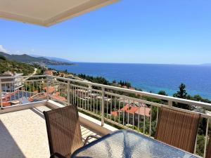 a balcony with a table and chairs and the ocean at Mega Panorama Apartments in Paleo Tsifliki