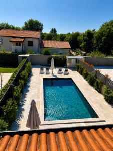 a swimming pool with two umbrellas next to a house at Casa ZOMABRIA in Poreč