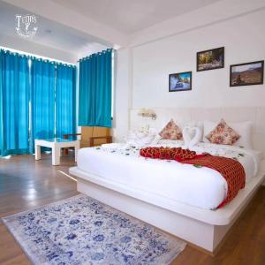 a large white bed in a room with blue curtains at Tethys Himalaya Resort in Solan