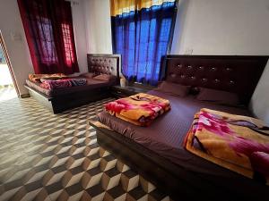 two beds in a bedroom with red curtains at Bahram vatika in Sonprayag