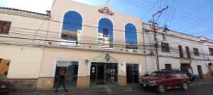 a person walking past a building with a red car in front at Colonia Real in Sucre