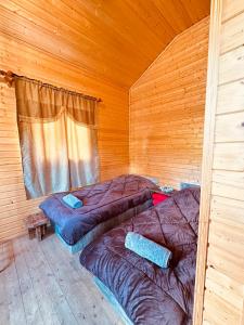 two beds in a room with wooden walls at SWEEPH in Mestia
