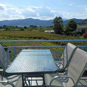 a table and chairs on a balcony with a view of a field at Enlightened Escape in Nea Peramos