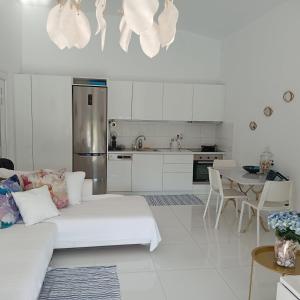 a white living room with a white couch and a kitchen at Enlightened Escape in Nea Peramos