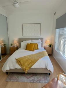 a bedroom with a large bed with a yellow blanket at Cosy and calm unit in Cronulla in Cronulla