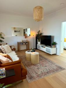 a living room with a couch and a flat screen tv at Cosy and calm unit in Cronulla in Cronulla