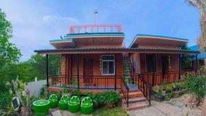 a small house with a balcony and some plants at PhaluaiHomestay พะลวยโฮมสเตย์ บ้านไม้ in Koh Phaluai