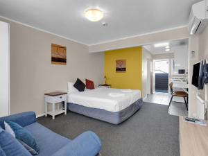 a hotel room with a bed and a living room at Kowhai Motel Rotorua in Rotorua