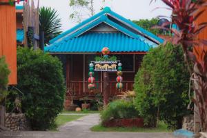 a sign in front of a house with a blue roof at PhaluaiHomestay พะลวยโฮมสเตย์ บ้านไม้ in Koh Phaluai