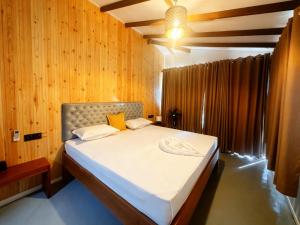 a bedroom with a bed in a room with wooden walls at Kumarana in Bentota