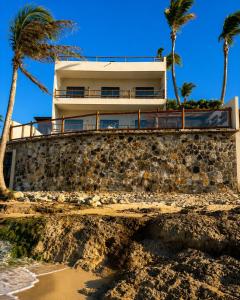 a house on top of a stone wall with palm trees at Dona Chica Wellness Center in Taíba