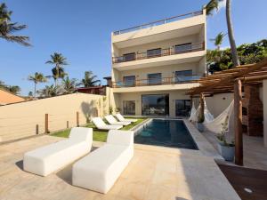 a villa with a swimming pool and white furniture at Dona Chica Wellness Center in Taíba