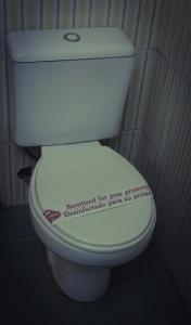 a bathroom with a toilet with a sticker on the lid at Colonia Real in Sucre